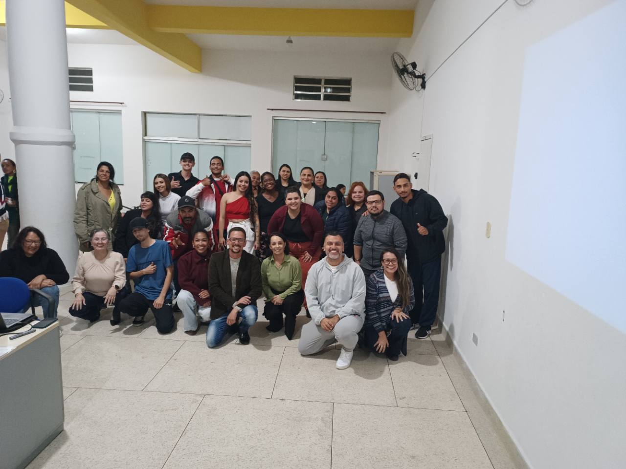Turma reunida na sala, com pessoas em pé e agachadas para a foto.